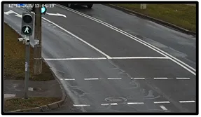 LPR camera view of an empty multi-lane road with a pedestrian signal pole in the foreground and a timestamp overlay