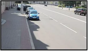 LPR camera view of a car parked at the curb of a residential street lined with shops and other parked vehicles