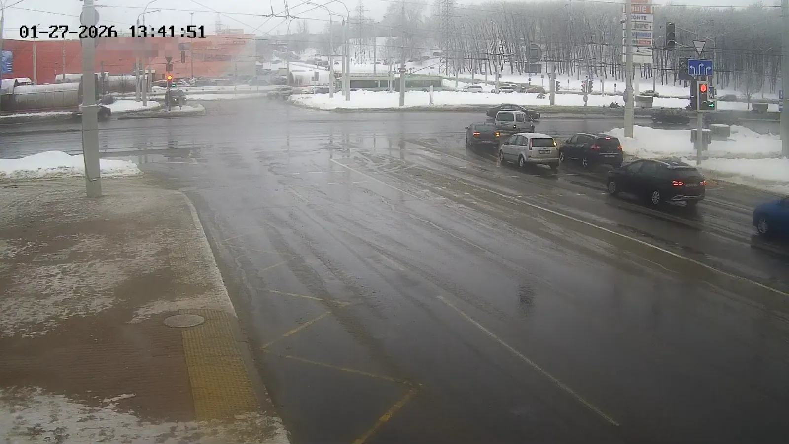 OV camera wide shot of a foggy road junction with several cars queued near a traffic light in a snowy setting